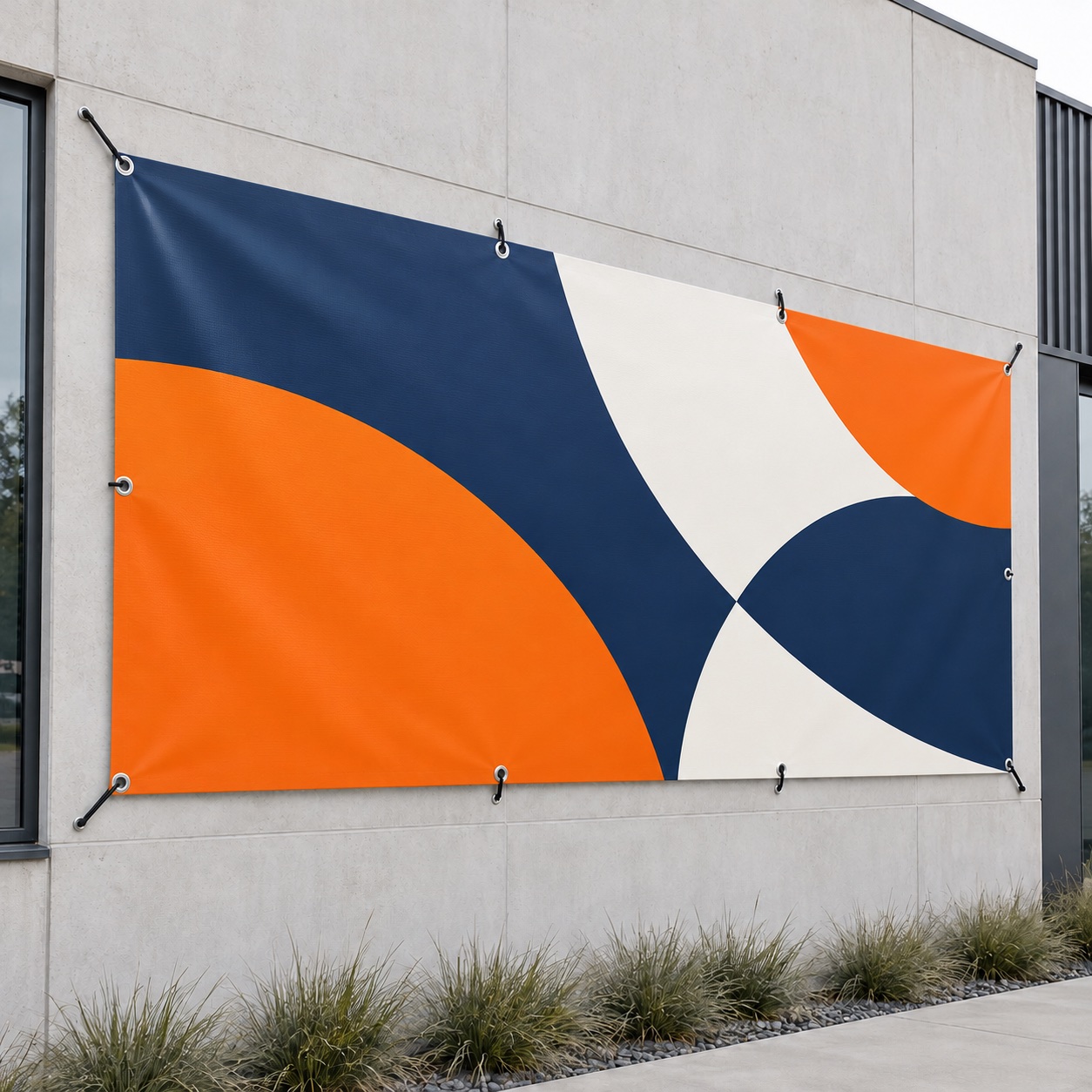 PVC spandoek met granat-oranje bedrukking en ringen gemonteerd aan een bedrijfsgevel